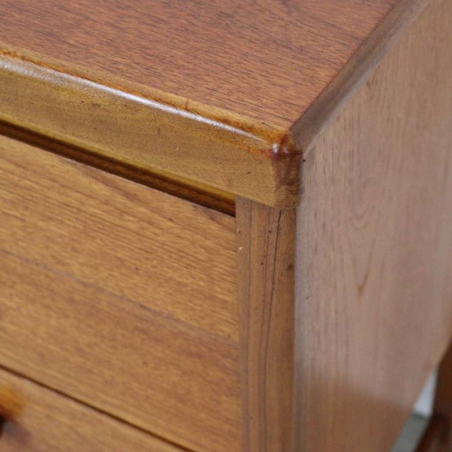 Close-up of vintage British mid-century teak sideboard corner showing smooth wood grain and rounded edges.