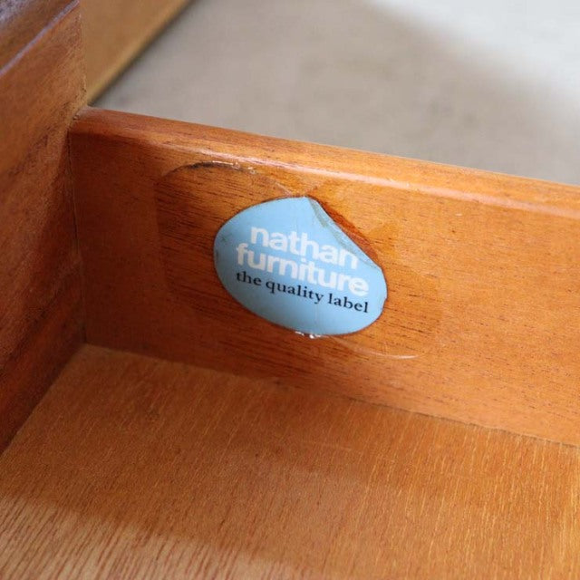 Close-up of vintage Nathan teak sideboard interior corner showing natural wood grain and original blue Nathan Furniture.
