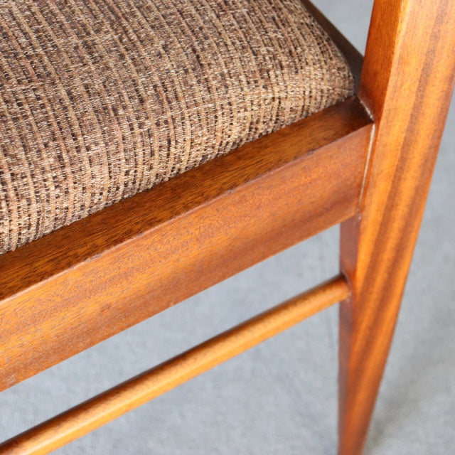 Mid-century British teak dining chair leg with warm wood grain and textured woven upholstery from McIntosh, Denmark style.