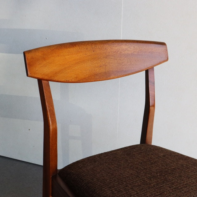 Mid-century British vintage dining chair in teak with gently curved backrest and dark brown fabric seat.