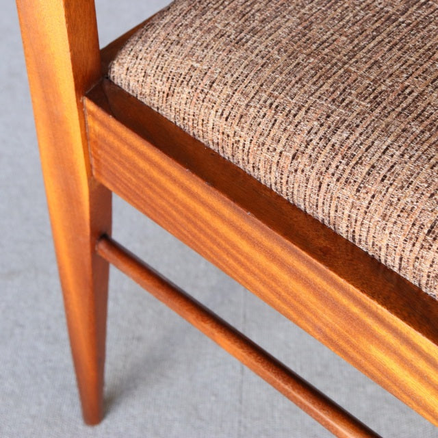 Mid-century British teak dining chair leg and frame with textured beige fabric seat, smooth wood grain, and slender tapered.