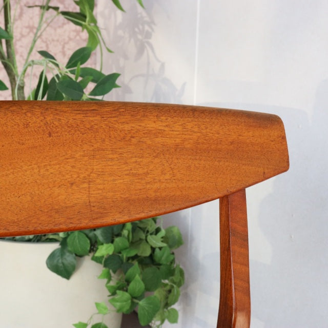 Vintage mid-century McIntosh teak dining chair backrest with smooth wood grain and slender legs.