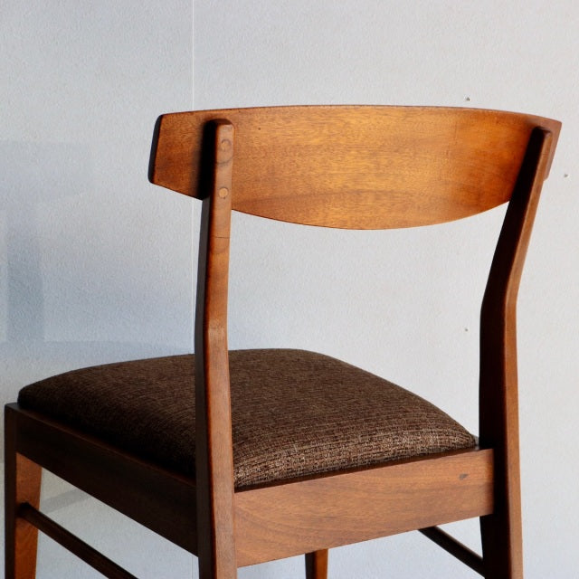 Vintage McIntosh teak dining chair with mid-century British design, curved backrest, and textured brown seat cushion.