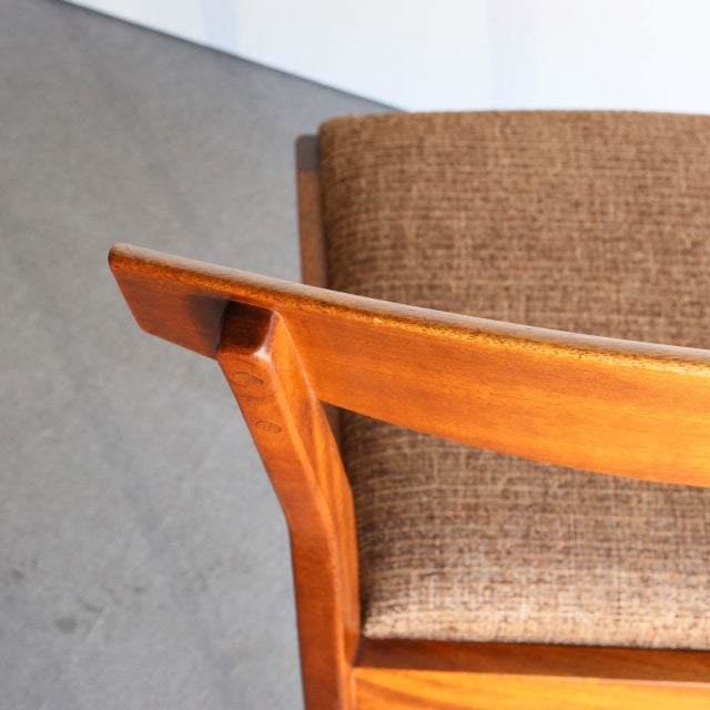 Mid-century British McIntosh dining chair in vintage teak with curved armrest and textured brown fabric seat against neutral .
