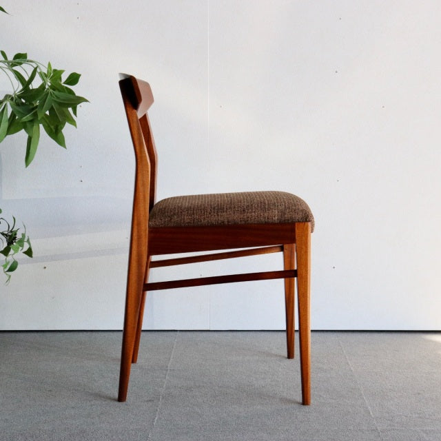 Mid-century British McIntosh teak dining chair with rich wood grain and brown upholstered seat, sleek angled legs from.