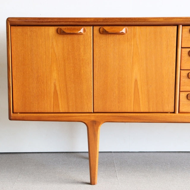 Mid-century British vintage teak sideboard by Younger with rich wood grain, tapered legs, and rounded wooden handles.