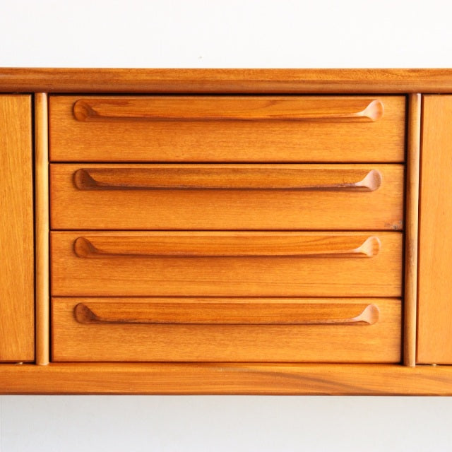 Mid-century British vintage teak sideboard by Younger with four smooth grain wood drawers and sculpted handles.