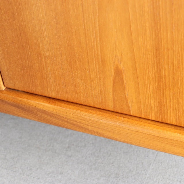 Close-up of vintage teak sideboard corner showcasing smooth wood grain and sleek mid-century British design legs.