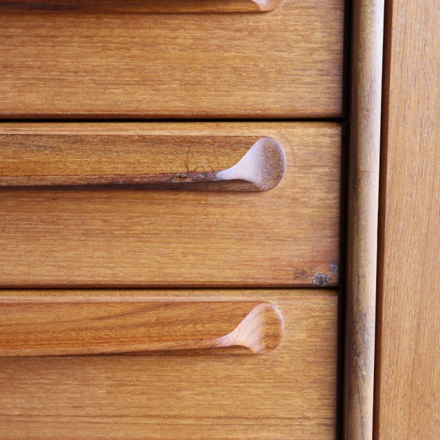 Close-up of vintage teak mid-century sideboard drawers by British-Danish brand Younger, showcasing warm wood grain and.