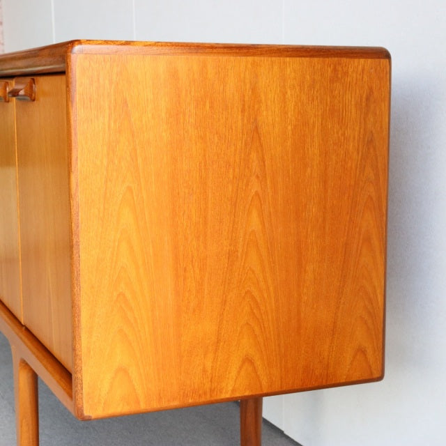 Mid-century British teak sideboard by Younger with rich wood grain and rounded edges, vintage Danish design.