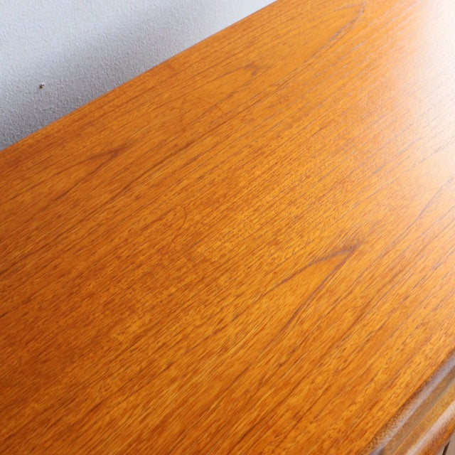 Close-up of vintage teak sideboard surface showing warm wood grain and smooth mid-century Danish finish.