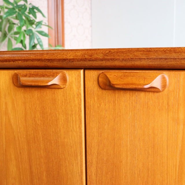 Mid-century British vintage teak sideboard by Younger with smooth wood grain and sculpted handles.