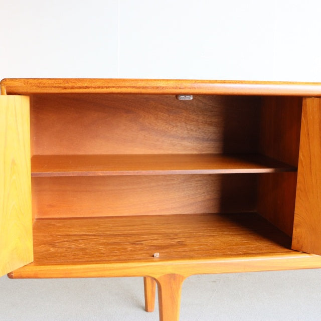 Vintage mid-century teak sideboard by Younger, British design with smooth wood grain, open interior shelving, and slender.