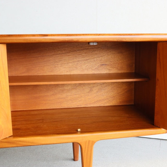 Mid-century vintage British teak sideboard by Younger with smooth wood grain, open storage, and slender tapered legs from.