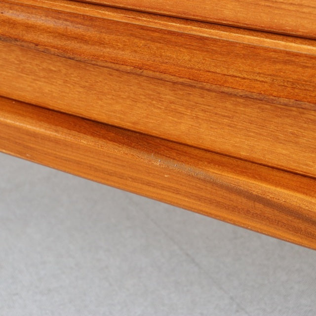 Close-up of vintage mid-century British teak sideboard corner showing smooth wood grain and warm honey tones with clean.
