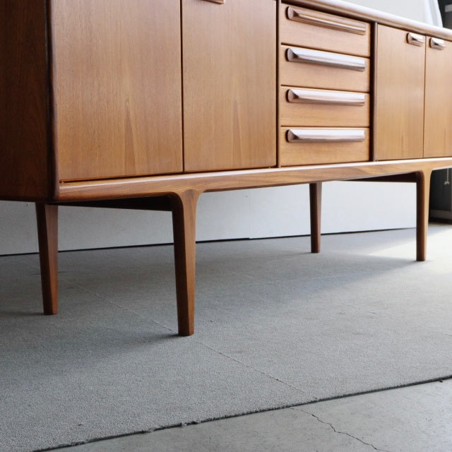 Mid-century vintage teak sideboard by Younger with smooth wood grain, slender tapered legs, and sleek British-Danish design.