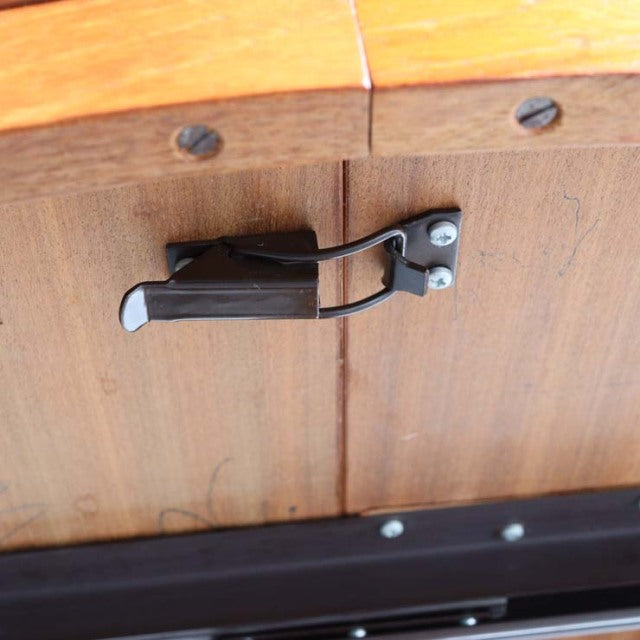 Close-up of vintage teak dining table latch mechanism featuring black metal hardware on British mid-century Denmark design.