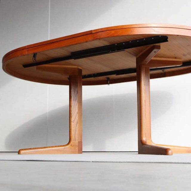 Vintage mid-century teak dining table by Edward Valentinsen with oval top and sturdy curved legs, showcasing rich wood grain .