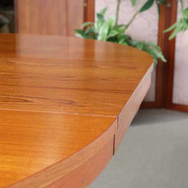 Close-up of vintage Edward Valentinsen teak round dining table edge showing smooth grain and warm mid-century Danish.