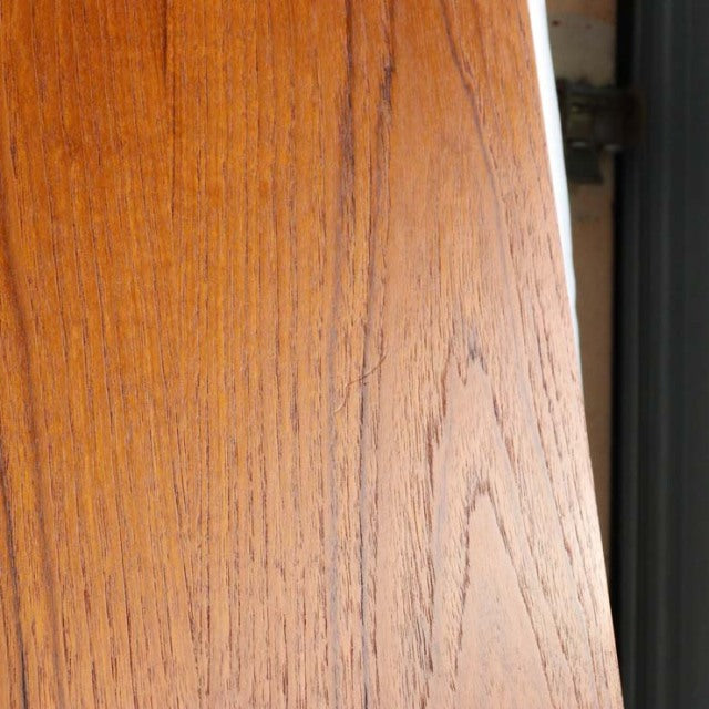 Close-up of vintage Edward Valentinsen teak dining table top showing rich wood grain and smooth round edge, mid-century.
