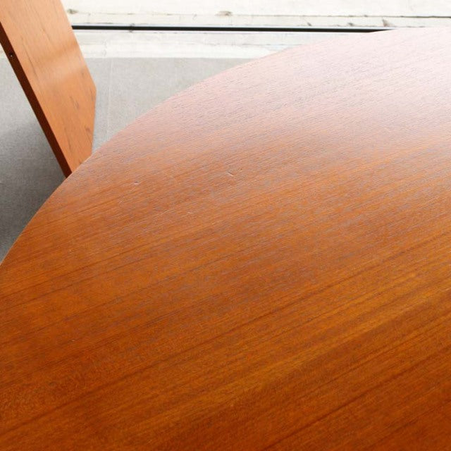 Vintage mid-century round teak dining table by Edward Valentinsen with smooth wood grain and slender tapered legs.