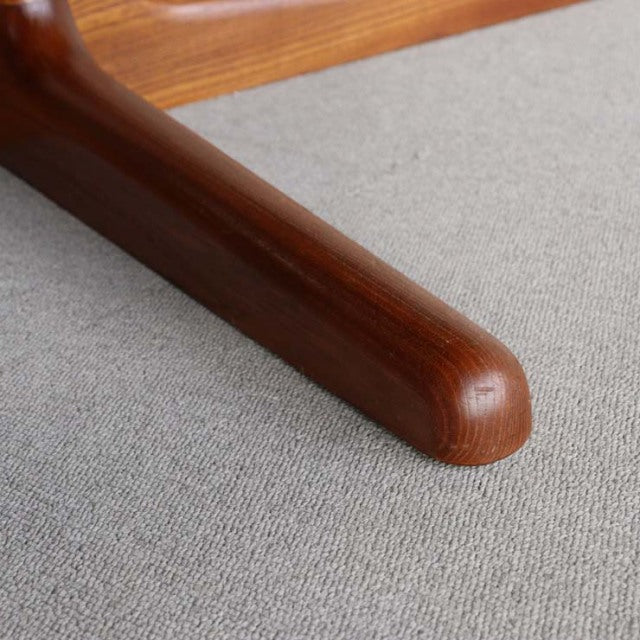 Close-up of rounded teak leg with smooth grain and warm brown finish on mid-century British vintage dining table.