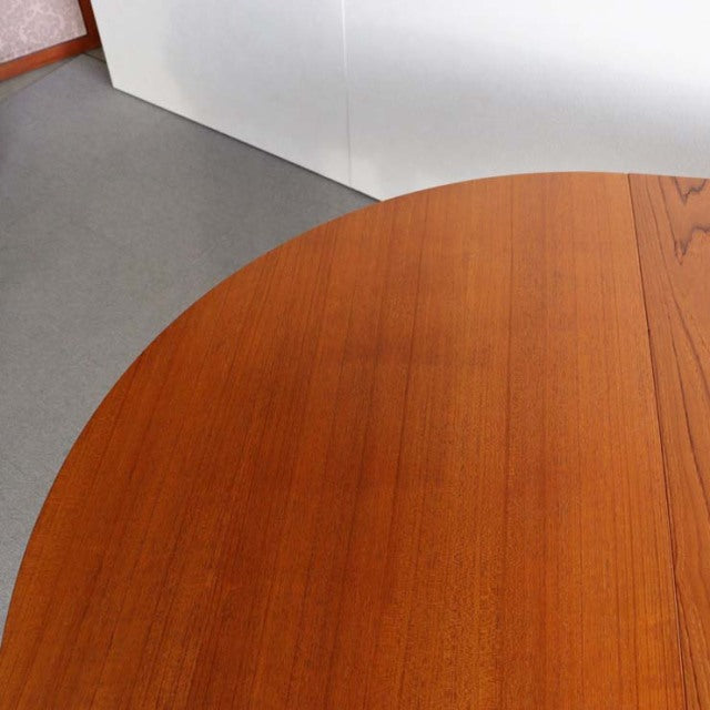 Round vintage teak dining table by Edward Valentinsen with smooth mid-century British-Denmark wood grain surface.