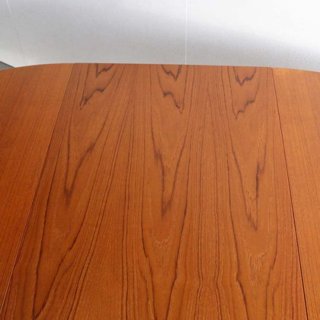 Vintage mid-century teak round dining table by Edward Valentinsen, smooth wood grain, slender tapered legs, Danish-British.