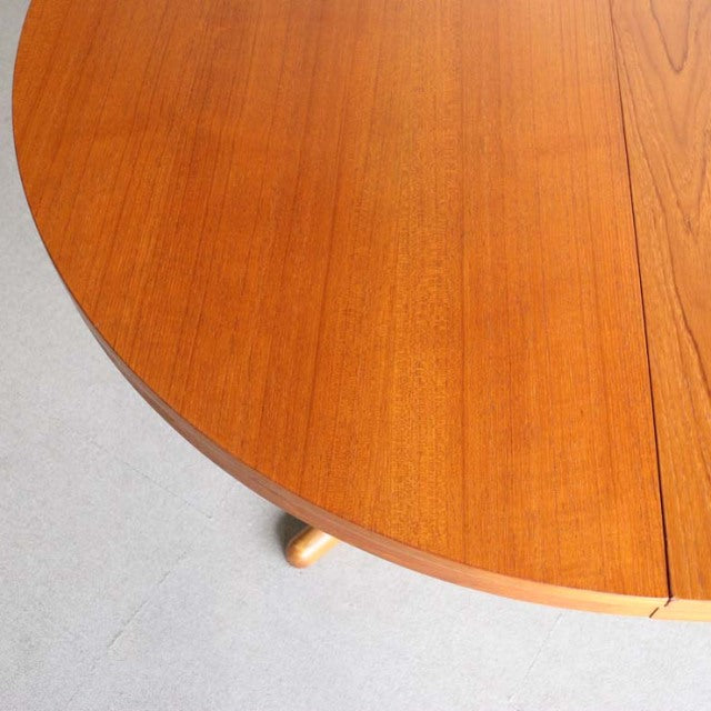 Round vintage teak dining table with smooth wood grain and tapered mid-century British Denmark legs.