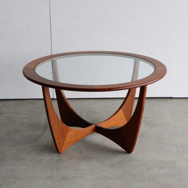 Vintage British mid-century teak coffee table with round glass top and sculptural curved wooden base.