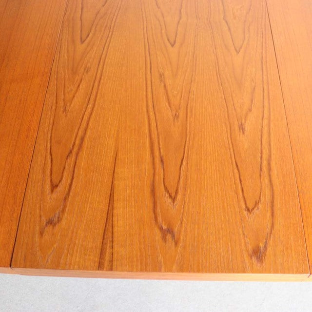 Close-up of vintage teak dining table surface showcasing rich wood grain and smooth mid-century British craftsmanship.