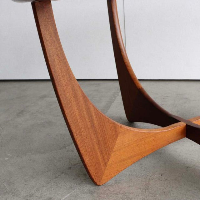 Mid-century British teak coffee table base with smooth curved legs and rich wood grain finish.