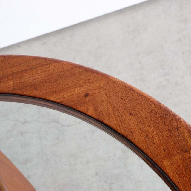 Close-up of vintage British teak coffee table edge with rich wood grain and round glass inset, mid-century design.