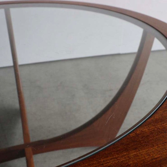 Mid-century British G-Plan Astrolound coffee table with teak frame and curved glass top, showcasing rich wood grain and.