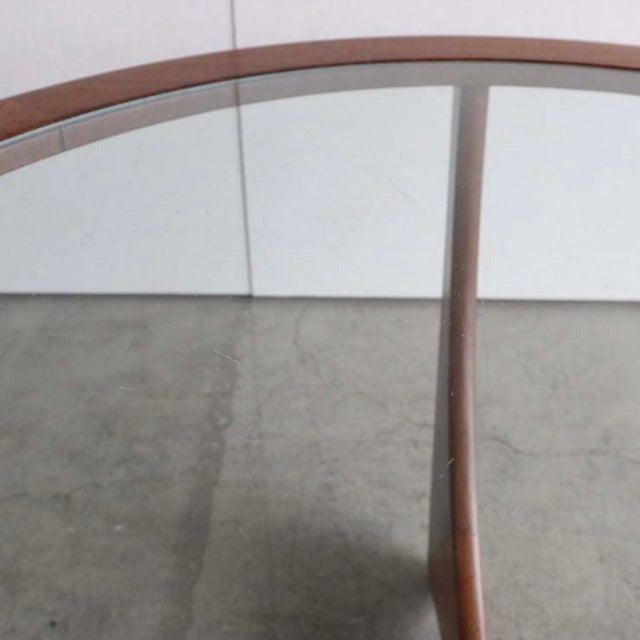 Vintage G-Plan teak coffee table with round glass top and mid-century British design, smooth wood grain visible on legs and.