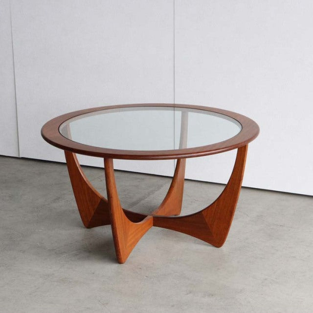 Vintage British mid-century G-Plan teak coffee table with round glass top and sculptural angled legs.