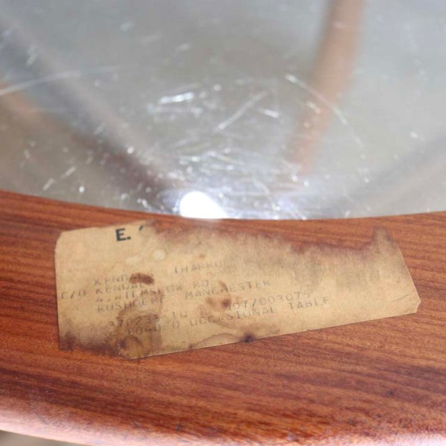 Close-up of vintage G-Plan teak coffee table with original worn paper label under glass top, mid-century British design.