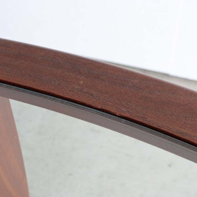 Close-up of vintage British mid-century G-plan teak coffee table edge with smooth oval glass top and rich wood grain.