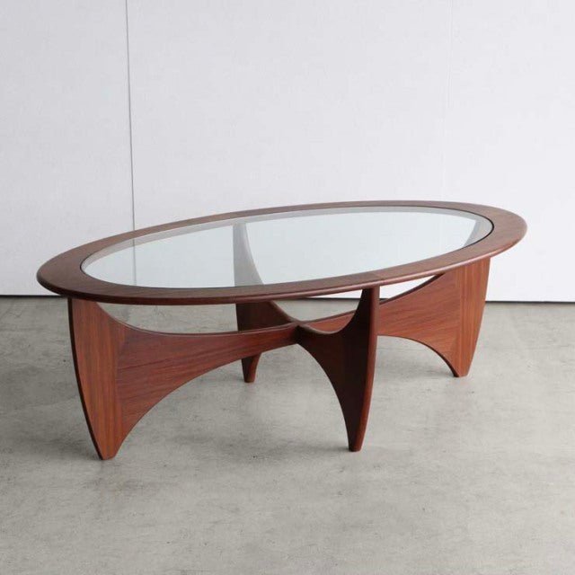 Vintage British mid-century G-Plan teak coffee table with oval glass top and sculpted curved legs showcasing rich wood grain .