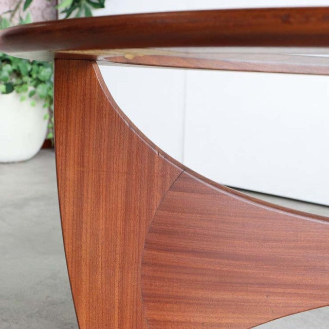Mid-century British vintage G-Plan teak coffee table with oval glass top and sculpted wooden legs showing rich wood grain.