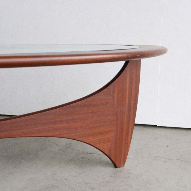 Mid-century British vintage G-Plan teak coffee table with oval glass top and sculpted wooden legs showing warm grain.