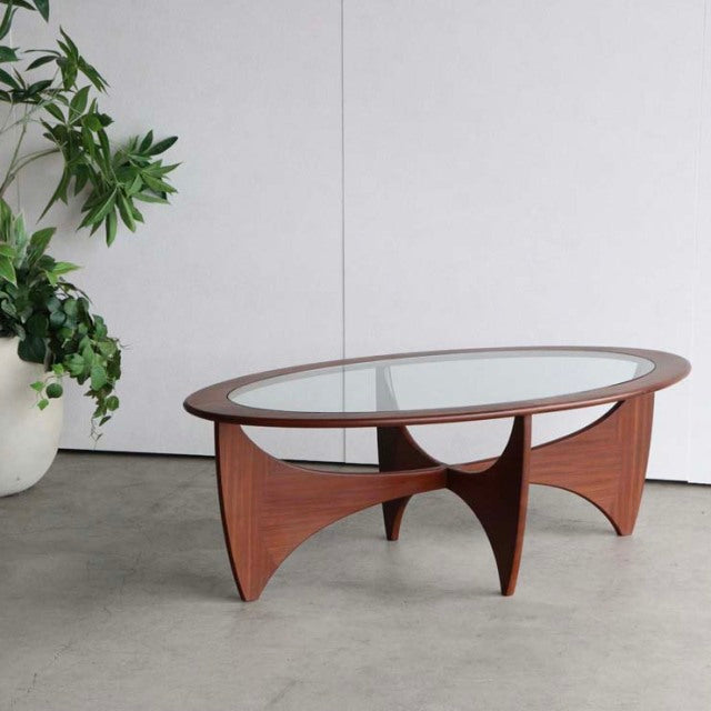 Mid-century British G-Plan teak coffee table with oval glass top, curved legs showcasing rich wood grain.
