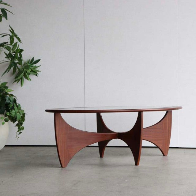 Mid-century British G-Plan teak coffee table with oval glass top and sculptural curved wood base, vintage Danish design.