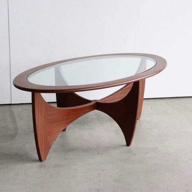 Oval mid-century British G-Plan teak coffee table with glass top, sculpted curved legs, and smooth wood grain.