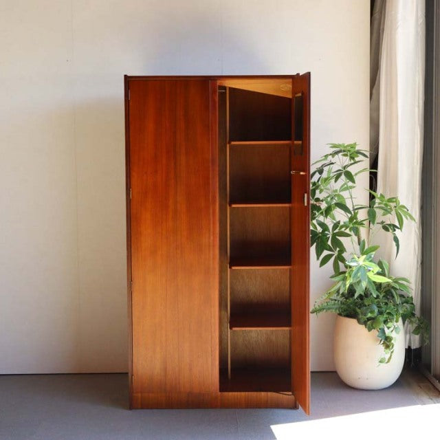 Mid-century British teak wardrobe by William Laurence with rich wood grain and tapered legs, open door revealing multiple.