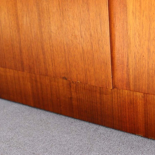 Close-up of vintage British mid-century teak cabinet highlighting warm wood grain and smooth finish at the base panel and.