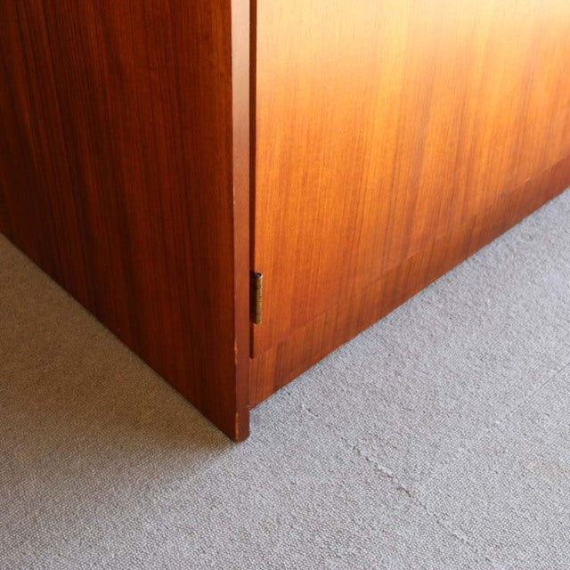 Corner close-up of vintage British mid-century teak cabinet showing rich wood grain and clean, angular lines on carpeted.