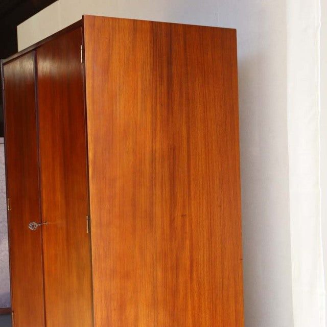 Vintage mid-century British teak cabinet by William Laurence with smooth wood grain and slender legs.