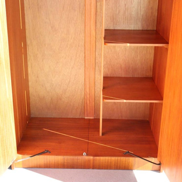 Mid-century British vintage teak wardrobe interior showing smooth wood grain, adjustable shelves, and sturdy base panel.