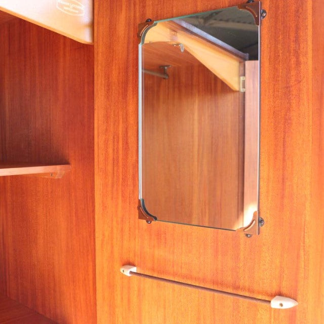 Vintage mid-century British teak wardrobe interior featuring smooth wood grain, corner brackets on rectangular mirror, and a .